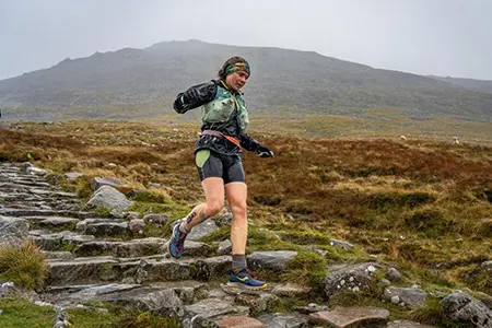 Lauren competing in a fell running race, skillfully navigating the challenging terrain on a misty day in the Lake District.